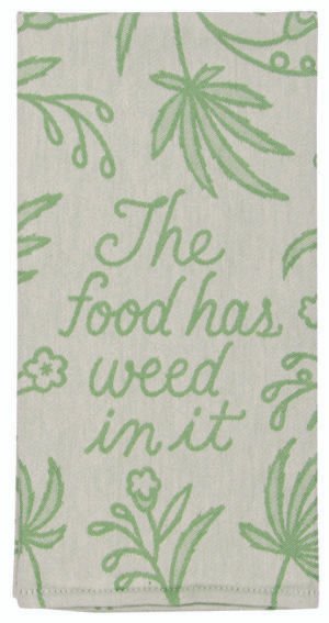 close up tea towel design in bright green tones, a floral background and cursive writing that says "the food has weed in it"